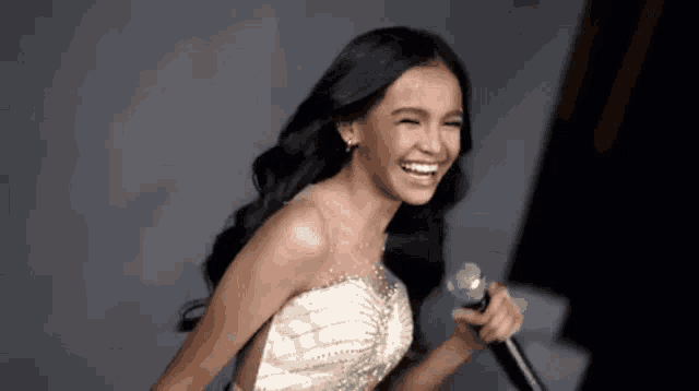 a woman is singing into a microphone and smiling