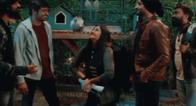 a group of people are standing around a woman dancing in front of a dog house .