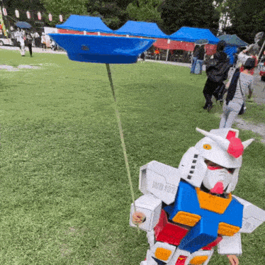 a child is dressed in a robot costume and holding a blue umbrella .