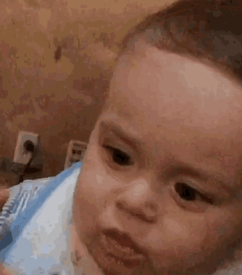 a baby is eating something with a spoon and making a funny face .
