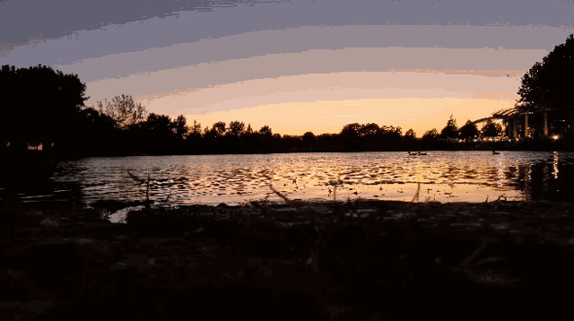 sunset over a lake with a bridge in the background