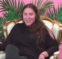 a woman is sitting in a chair with her legs crossed and a palm tree in the background .