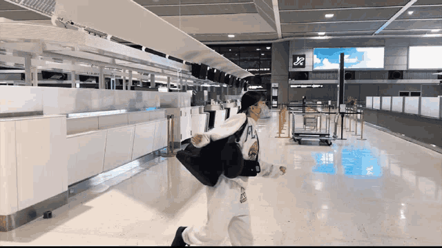 a woman wearing a mask runs through an airport terminal