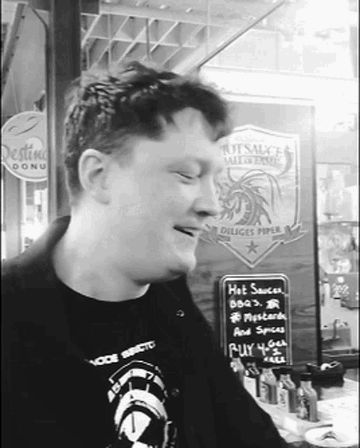 a man standing in front of a sign that says hot sauce on it