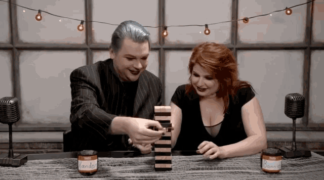 a man and a woman are playing jenga with jars of vanilla and chocolate