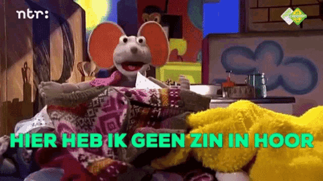 a stuffed mouse sits on a pile of blankets with the words hier heb ik geen zin in hoog