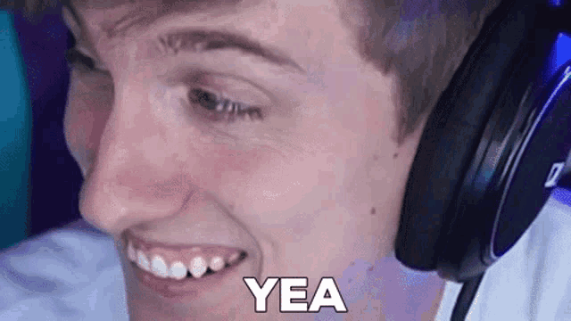 a young man wearing headphones is smiling and says yea .