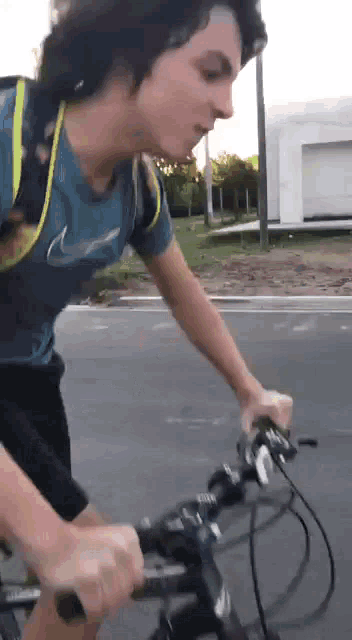 a man wearing a nike shirt is riding a bike down a street