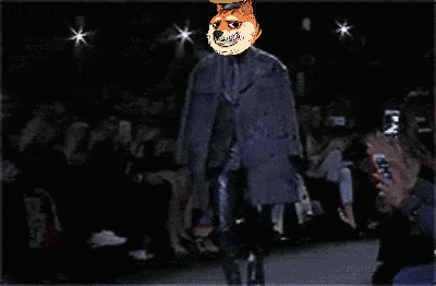 a man with a doge face on his head walks down the runway