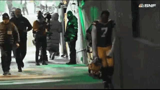 a football player with the number 7 on his jersey walks through a tunnel