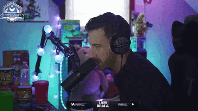 a man wearing headphones is talking into a microphone with the words i am bpala on the bottom