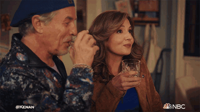 a man and a woman drinking from a glass with the nbc logo in the background
