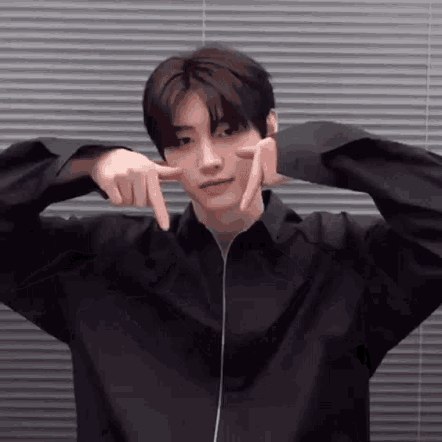 a young man in a black shirt is making a funny face with his fingers .