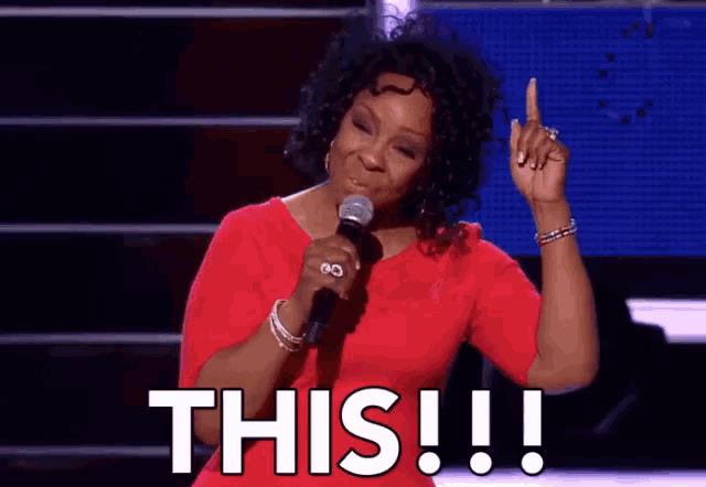 a woman in a red dress is holding a microphone and saying this