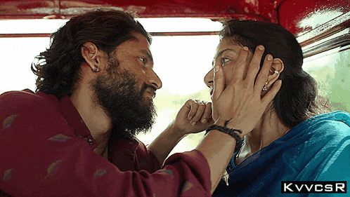a man with a beard is touching a woman 's face and the letters kvvcsr are below him
