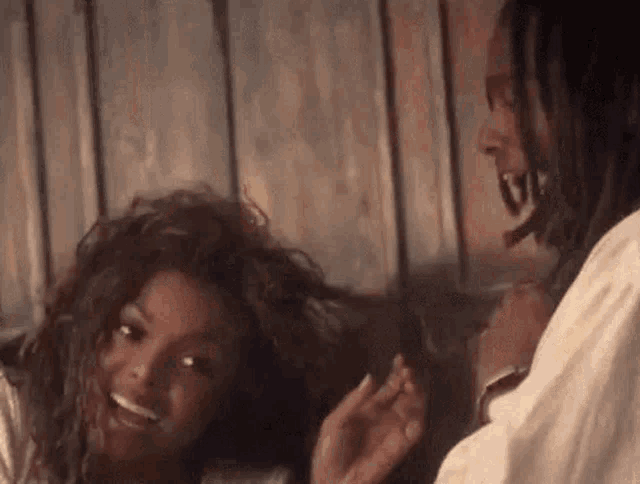 a man is brushing a woman 's hair while they are laughing and smiling .