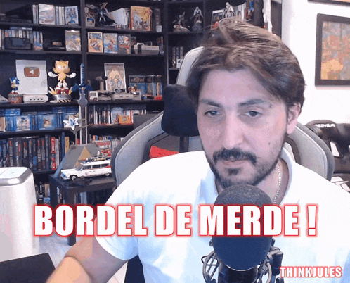 a man sitting in front of a microphone with the words bordel de merde written above him