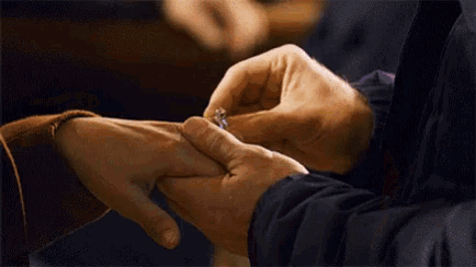 a man is putting an engagement ring on the finger of a woman .