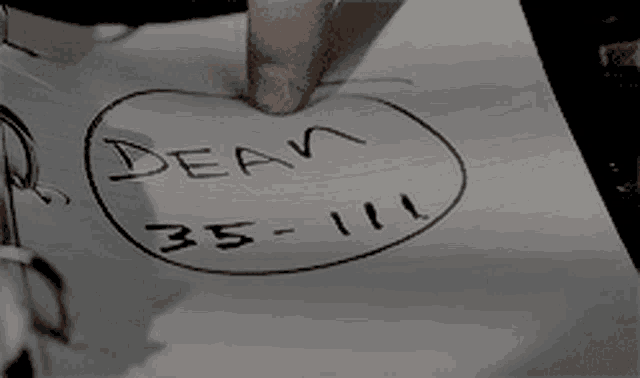 a person is writing on a piece of paper that says dean