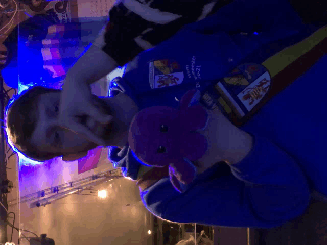 a man holding a stuffed animal wearing a blue shirt that says ' i.c.c. ' on it