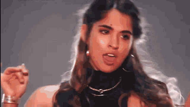 a woman with long hair is wearing a black top and earrings