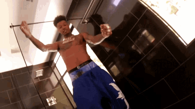 a man without a shirt is standing in a bathroom wearing blue shorts that say calvin klein