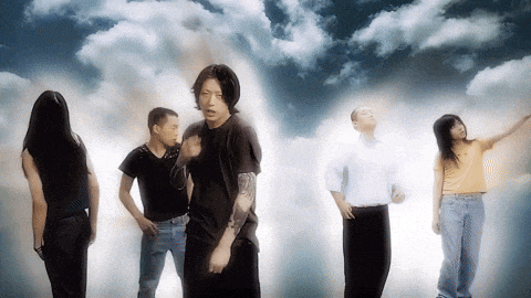 a group of people standing in front of clouds