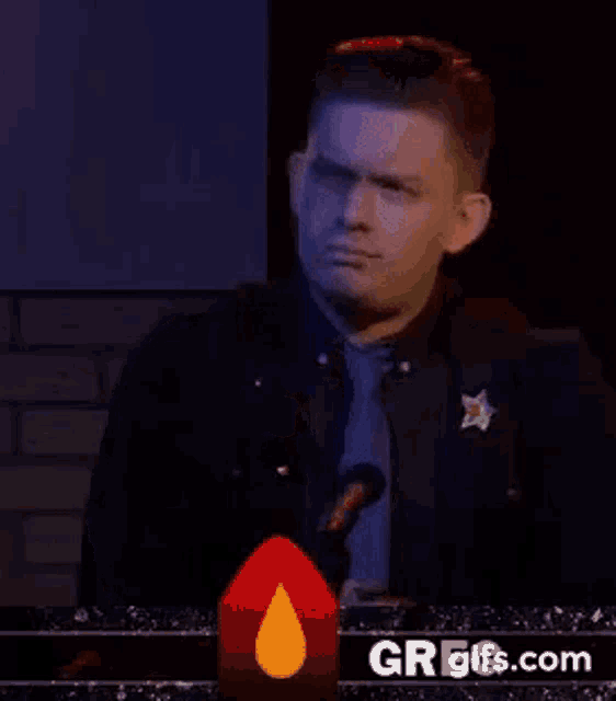 a man in a sheriff 's uniform is holding a microphone in front of a candle .