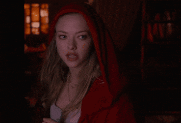 a woman in a red hood is looking at something in the dark