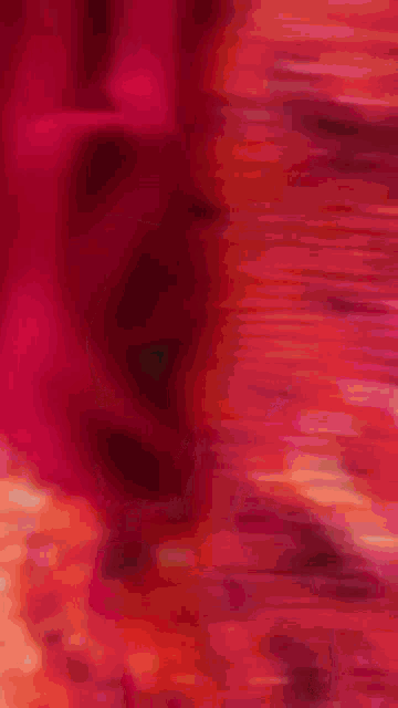 a person is laying on a bed with a red and orange blanket on it .