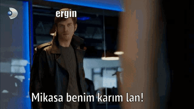a man in a black leather jacket is standing in front of a sign that says " ergin "