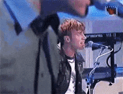 a man is singing into a microphone while sitting at a keyboard .
