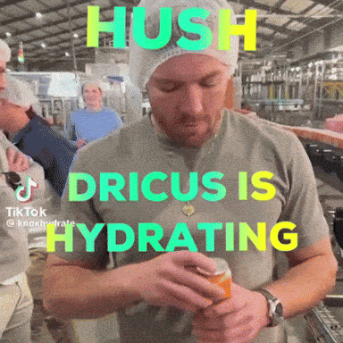 a man in a grey shirt with the words hush dricus is hydrating on the front