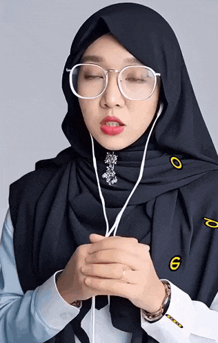 a woman wearing a hijab and glasses has the number 6 on her sleeve