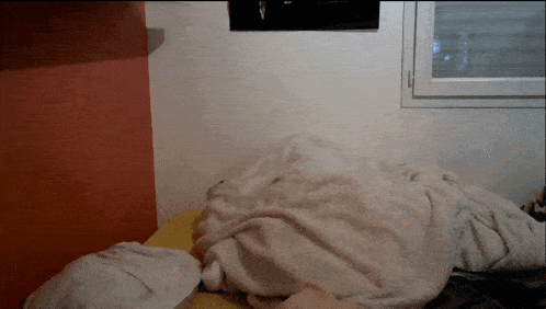 a person is laying on a bed with a blanket on top of them