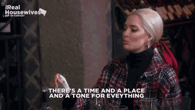 a woman is sitting at a table with a bottle of wine and says there 's a time and a place