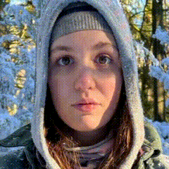 a woman wearing a hooded jacket and a beanie is standing in the snow