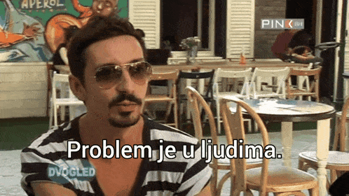 a man wearing sunglasses says problem je u ljubima in front of tables and chairs