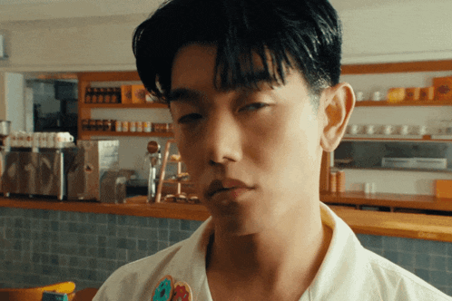 a young man wearing a white shirt with a bear pin on his chest