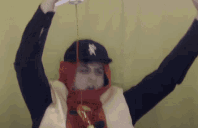 a person wearing a hat with the letter x on it is pouring ketchup from a bottle