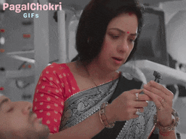 a woman wearing a red blouse and a silver and black saree is sitting in a chair