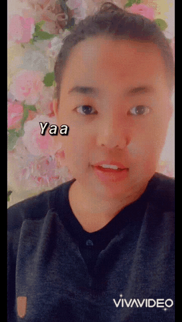 a young man with flowers in the background says yaa