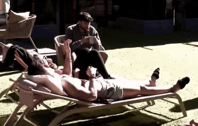 a man sits in a chair next to a woman laying on a chair