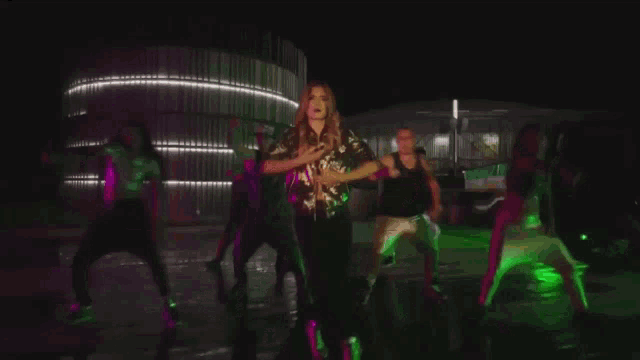 a group of people are dancing in front of a building