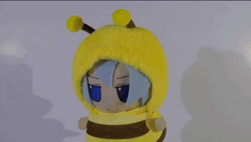 a stuffed animal wearing a bee costume is standing on a table .