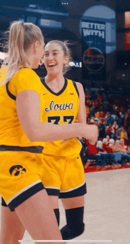 two female basketball players from iowa are hugging each other on the court