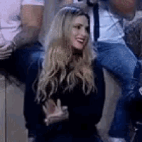 a woman is sitting in front of a group of people applauding and smiling .