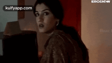 a woman is standing in a room with a laptop in her hand .