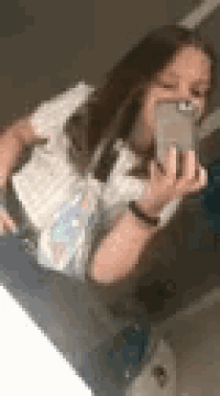 a woman is taking a selfie with her cell phone in a bathroom .