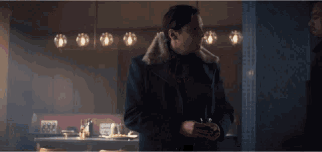 a man with a fur collar is standing in a dark room
